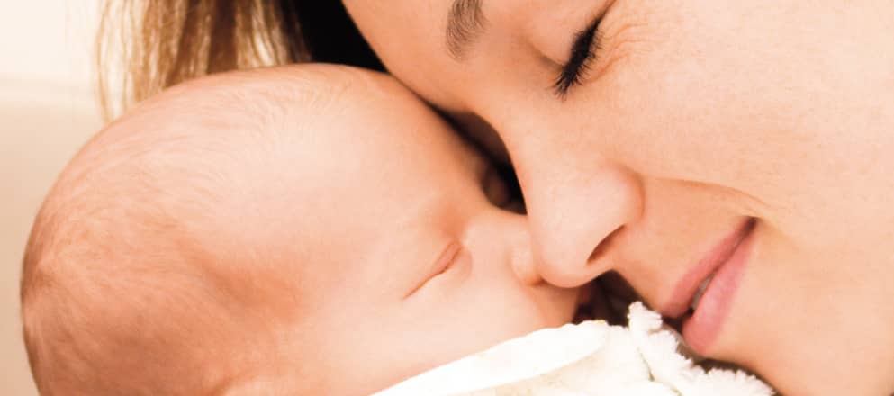 Een vrouw knuffelt haar pasgeboren kind