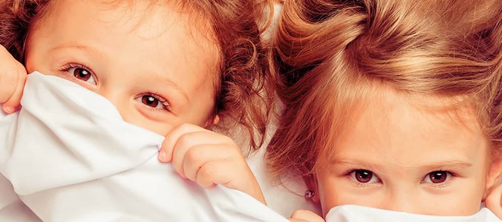 kinderen met hun hoofd net boven de lakens