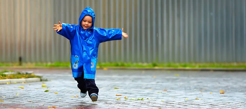 kind speelt in de regen