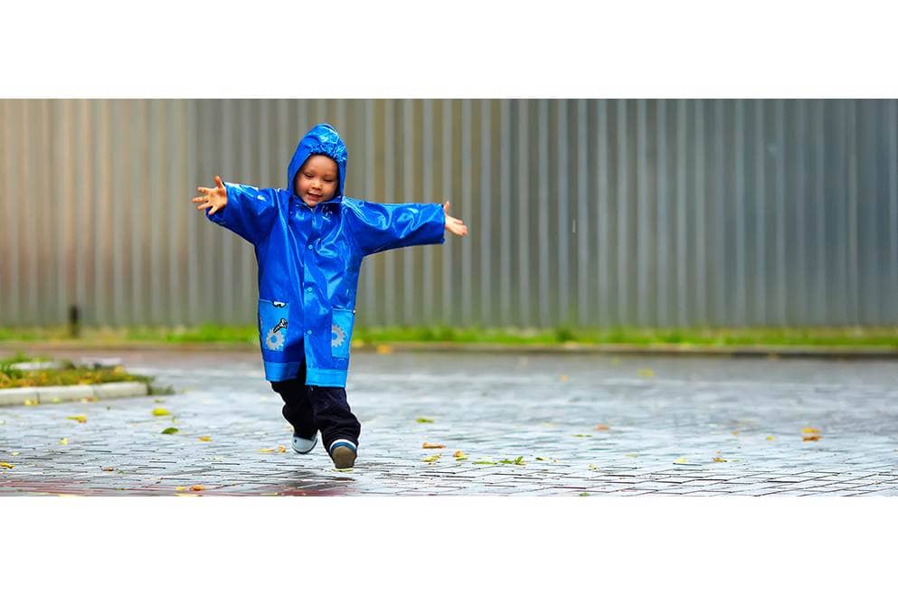 kind speelt in de regen