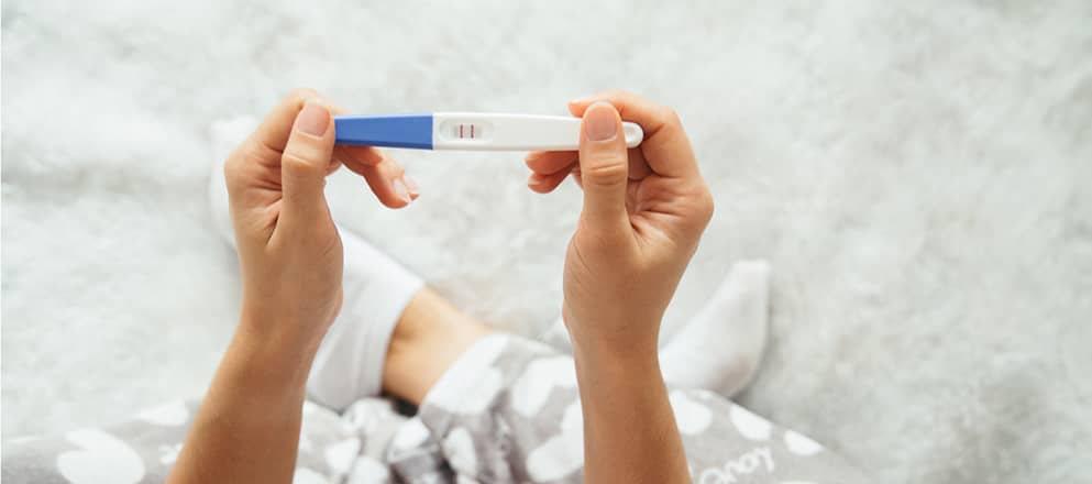 Een vrouw kijkt op een positieve zwangerschap test