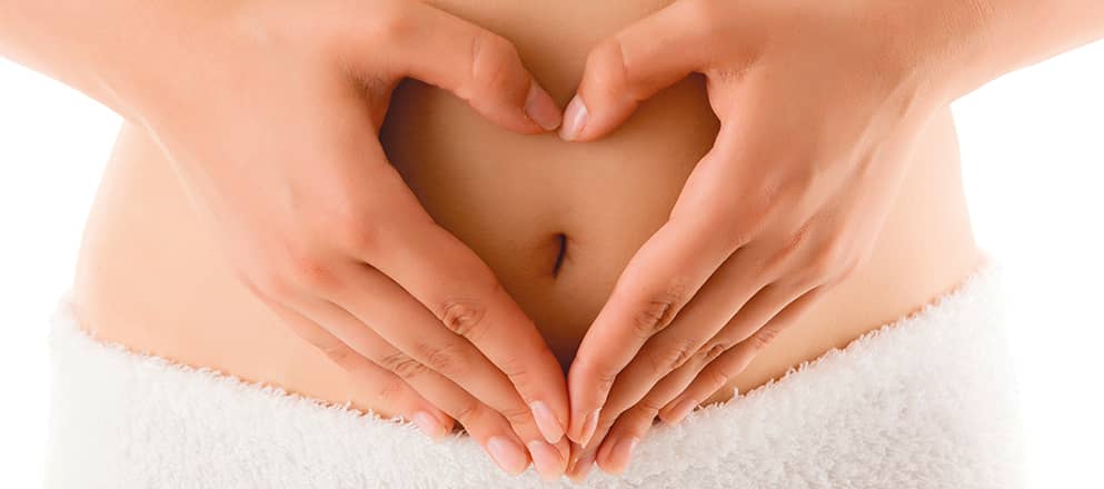 vrouw vormt hartje met haar handen voor haar buik